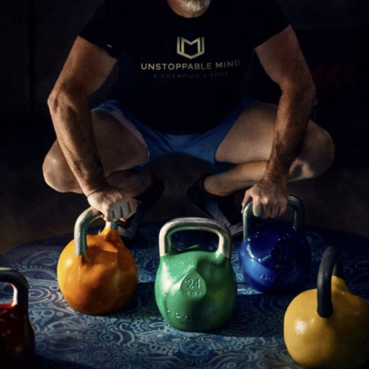 Man squatting with colorful kettlebells on a dark surface